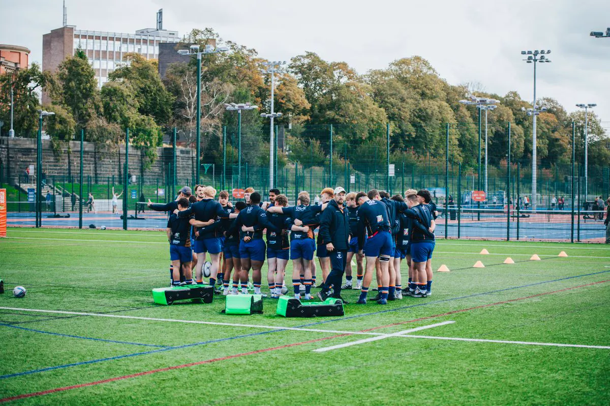 A junior football squad in a huddle on a 3G pitch